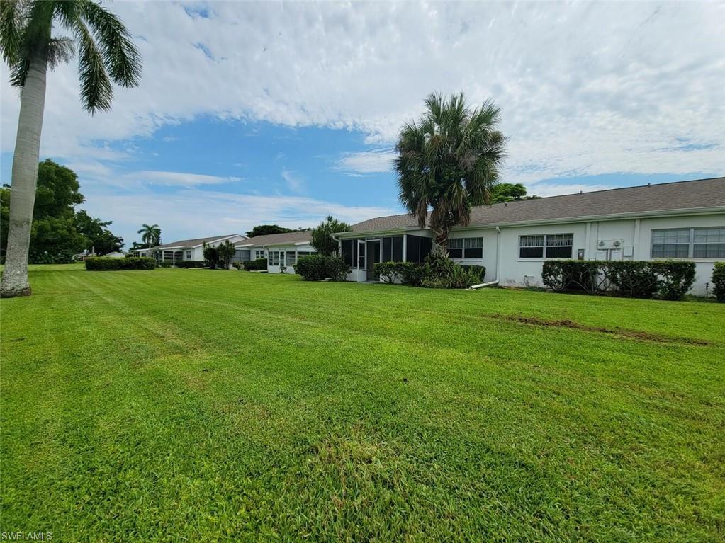 View of grassy yard featuring a sunroom