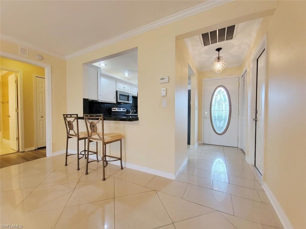 Entrance foyer with crown molding and light tile patterned floors