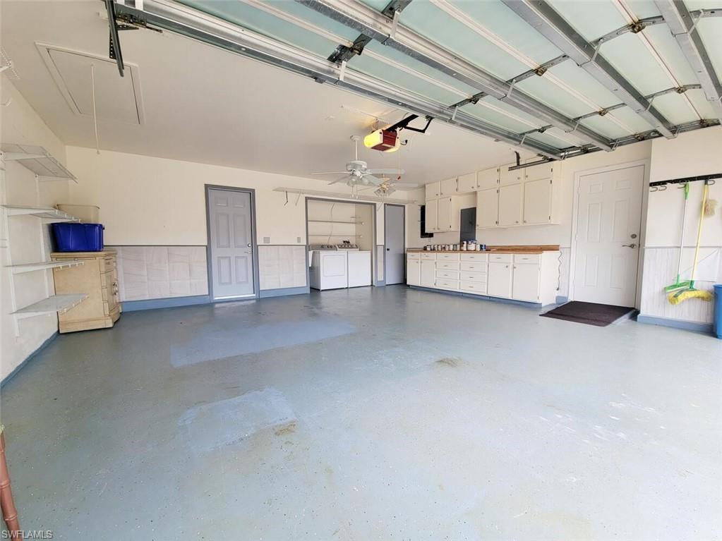 Garage featuring washer and clothes dryer, a garage door opener, and electric panel