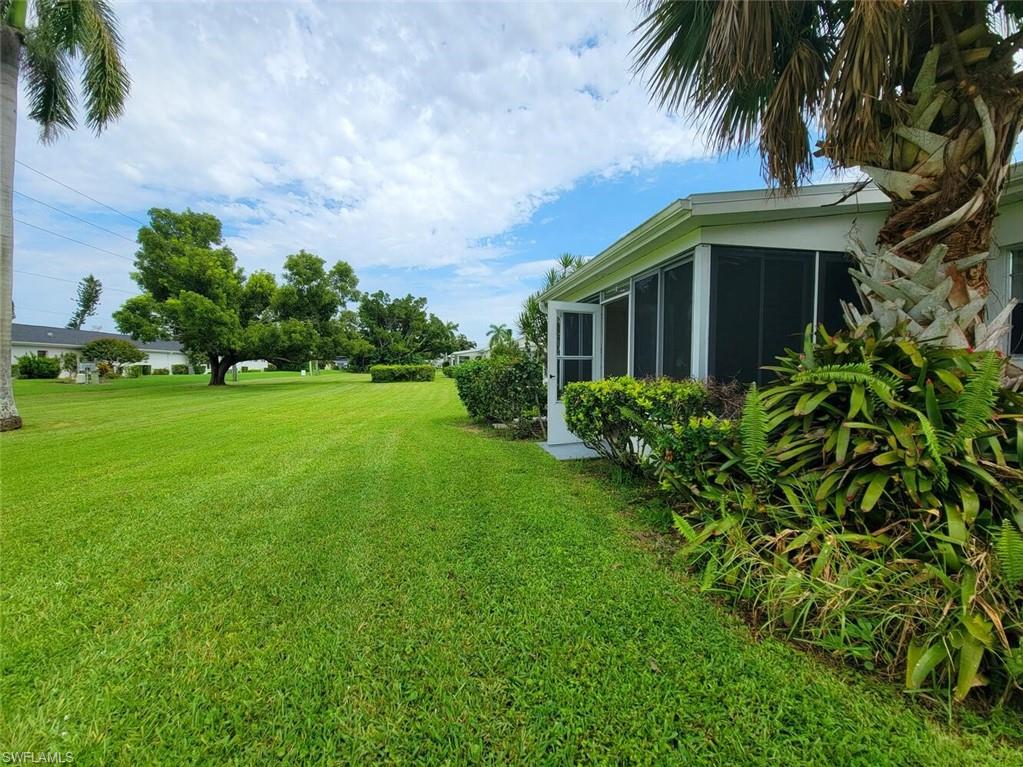 View of grassy yard with a sunroom