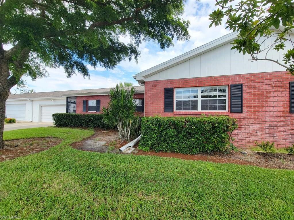 Ranch-style home featuring a front lawn, brick siding, a garage, and concrete driveway