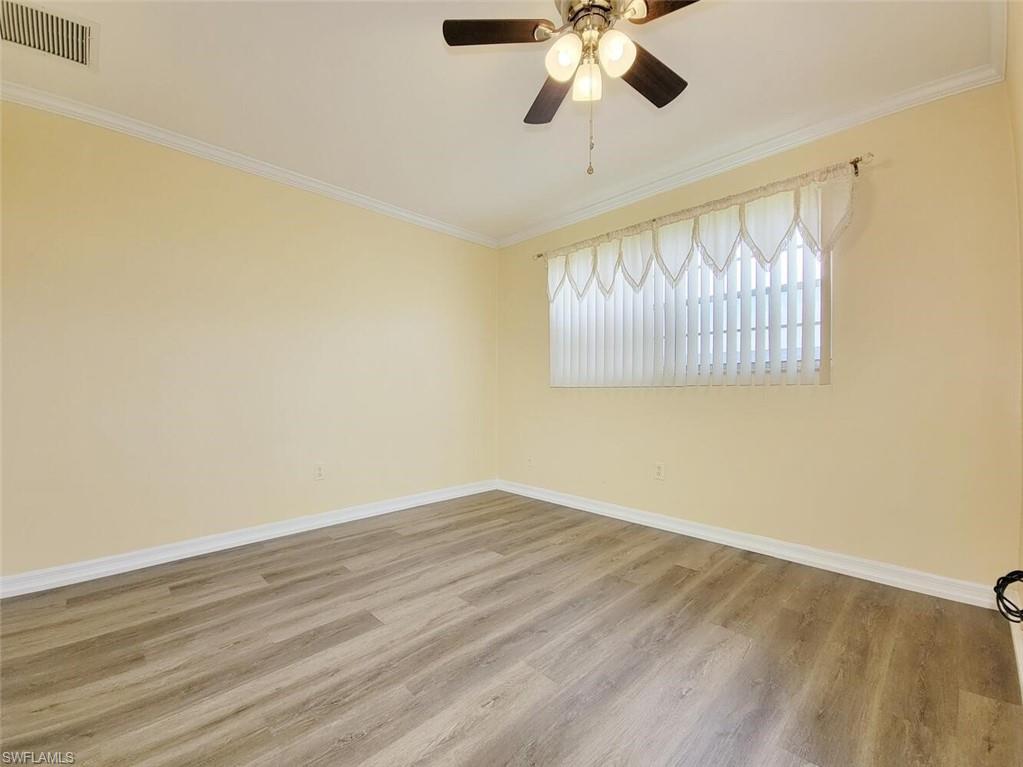 Empty room featuring crown molding, light wood-style floors, and ceiling fan