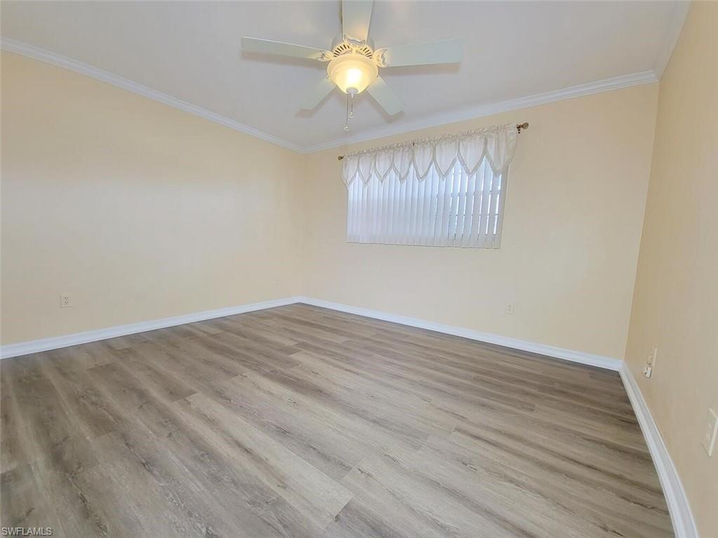 Empty room with ornamental molding, light wood-style floors, and ceiling fan