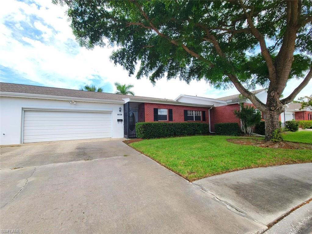 Ranch-style house with a front lawn, driveway, an attached garage, stucco siding, and brick siding