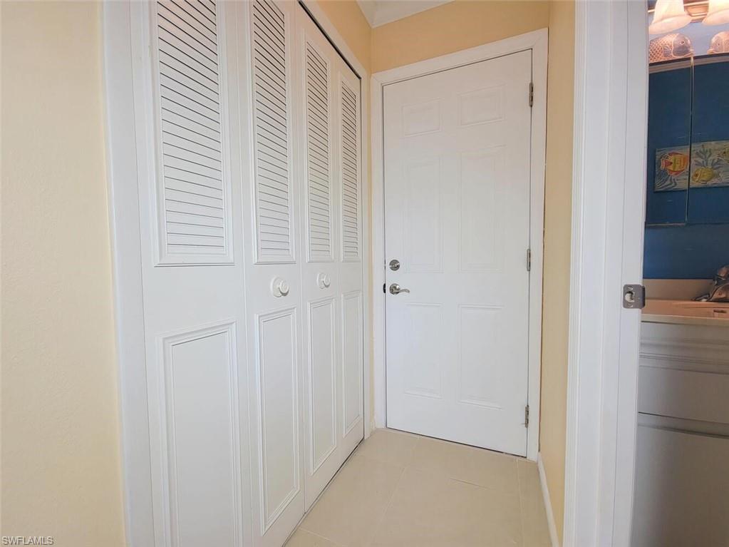 Hallway featuring light tile patterned floors and a sink