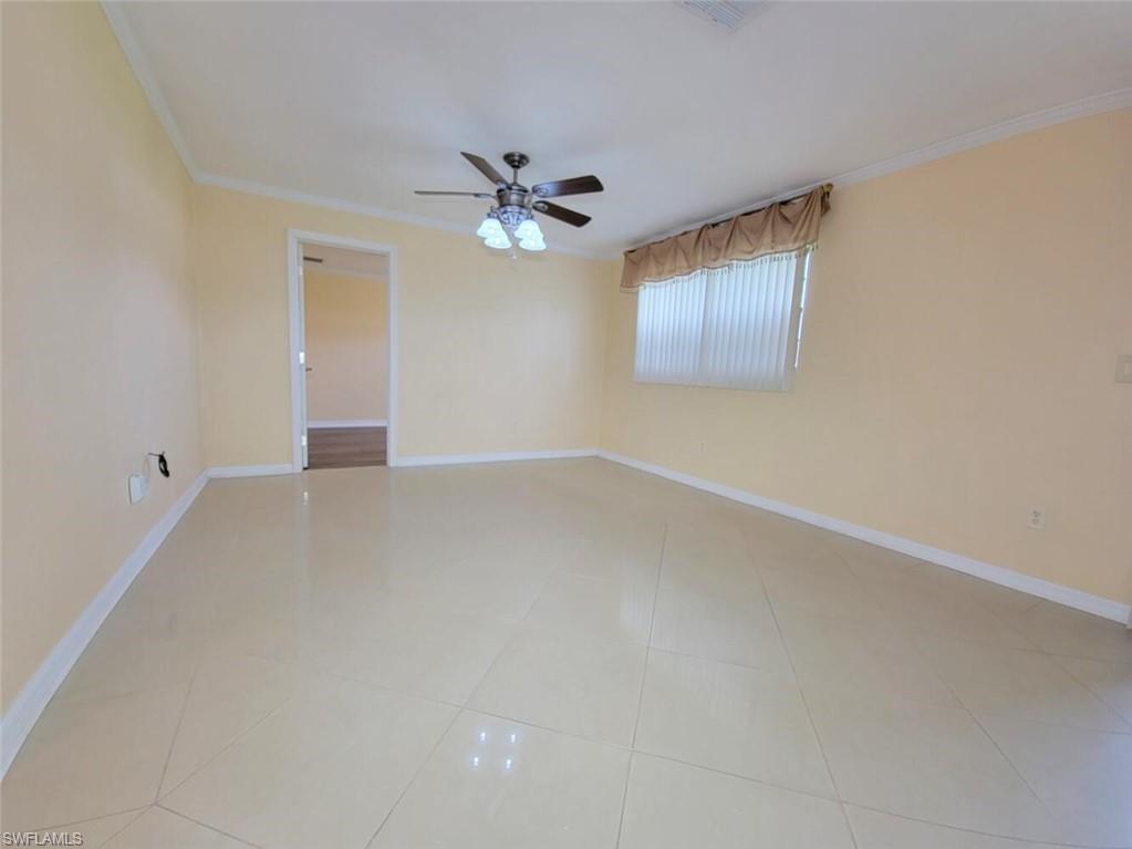 Spare room with crown molding, light tile patterned floors, and ceiling fan
