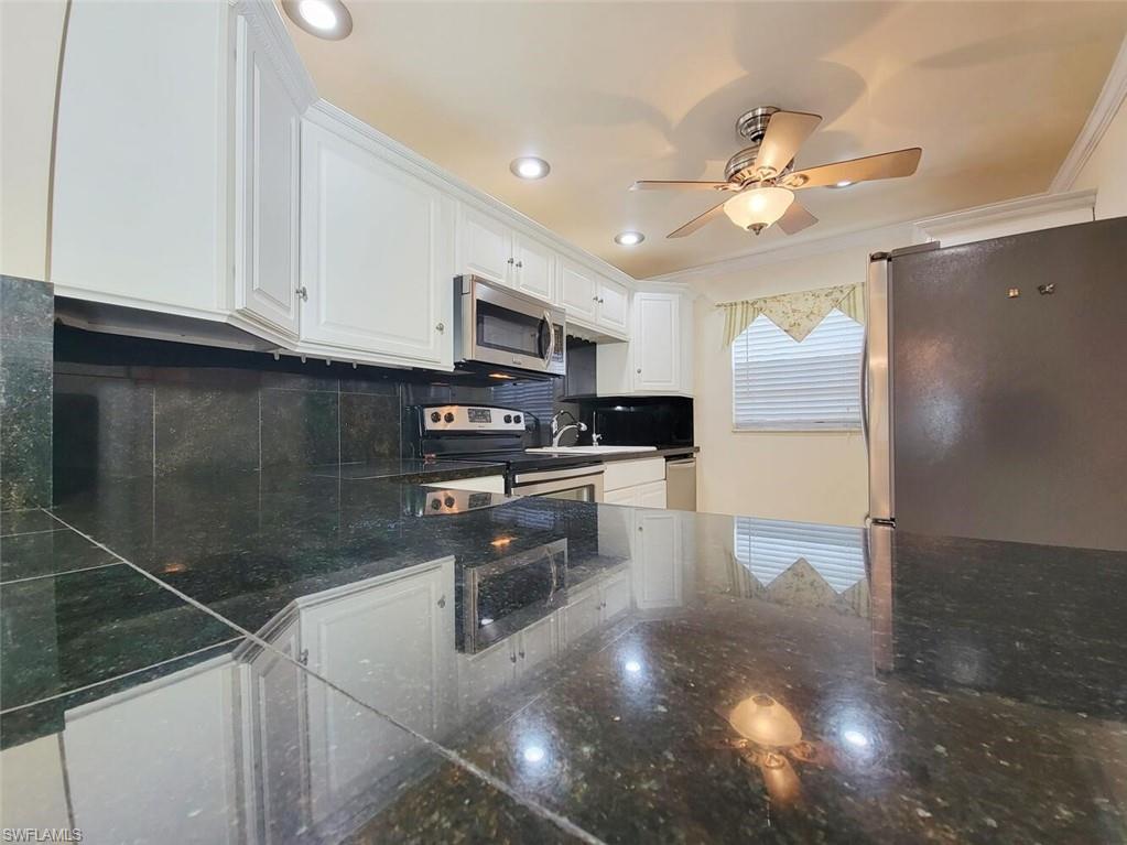 Kitchen with decorative backsplash, white cabinets, ornamental molding, stainless steel appliances, and recessed lighting