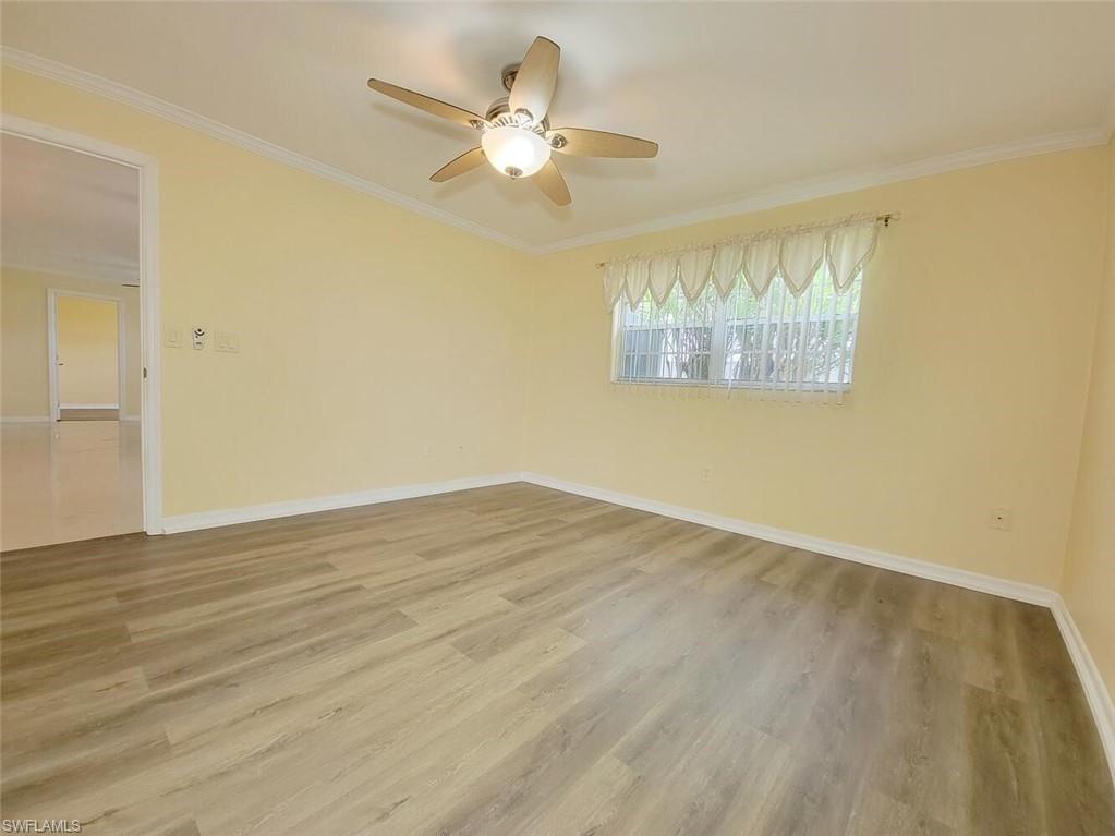 Empty room featuring crown molding, light wood-style floors, and ceiling fan