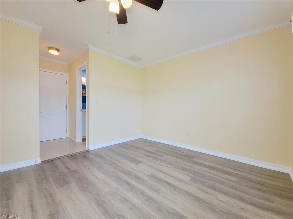 Empty room featuring crown molding, light wood-style flooring, and ceiling fan