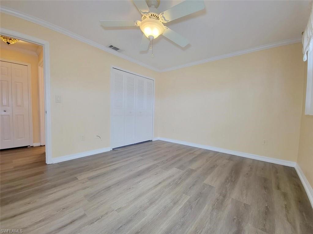 Unfurnished bedroom with ornamental molding, light wood-type flooring, a ceiling fan, and a closet