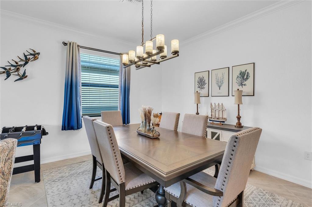 Dining area featuring ornamental molding, light tile patterned flooring, and a chandelier