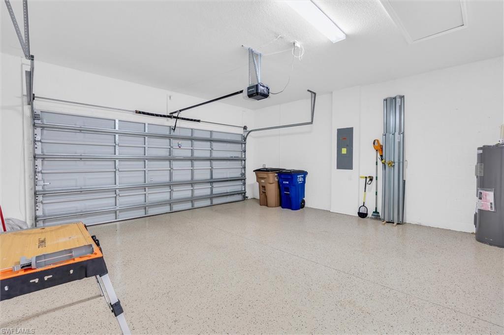 Garage featuring electric panel, water heater, and a garage door opener