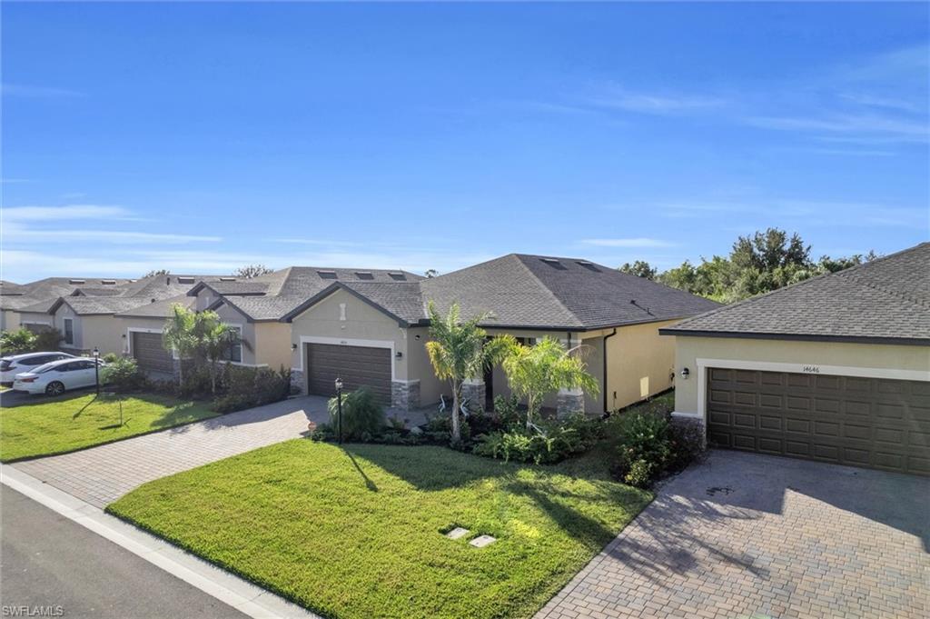 View of front of house with stucco siding, a front yard, and decorative driveway