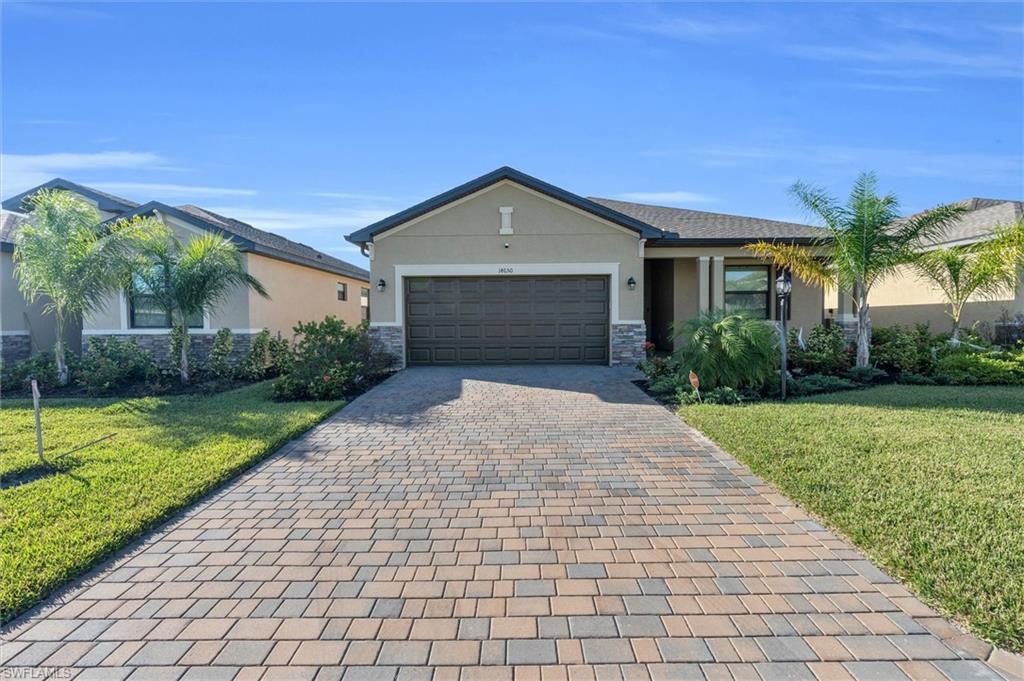 Ranch-style home featuring stone siding, a front yard, stucco siding, and decorative driveway