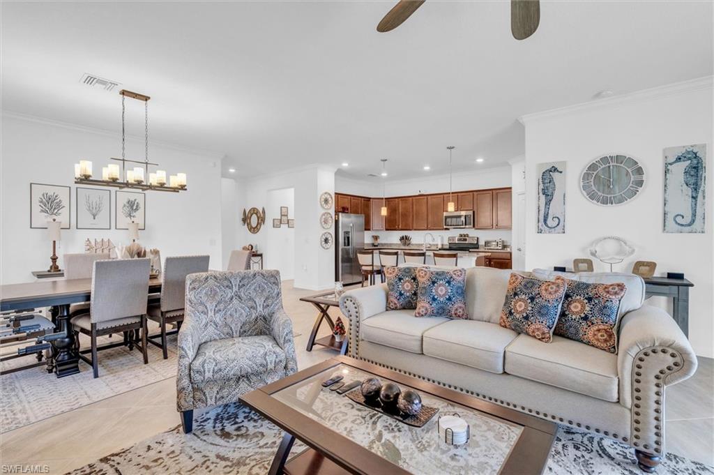 Living area featuring ornamental molding, recessed lighting, light tile patterned floors, a chandelier, and a ceiling fan