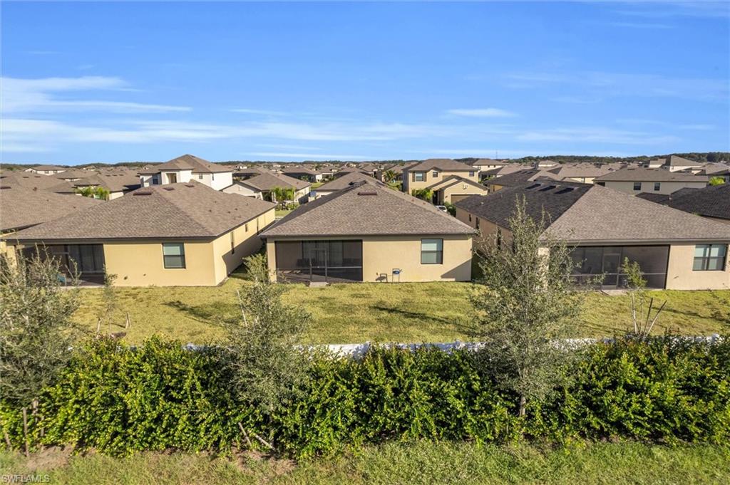 Rear view of property featuring a sunroom, a residential view, a lawn, and stucco siding