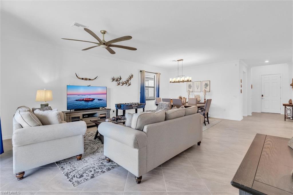 Living area featuring a ceiling fan, light tile patterned flooring, and ornamental molding