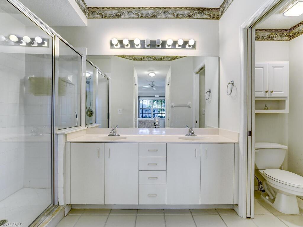Ensuite bathroom featuring double vanity, a shower stall, and light tile patterned flooring