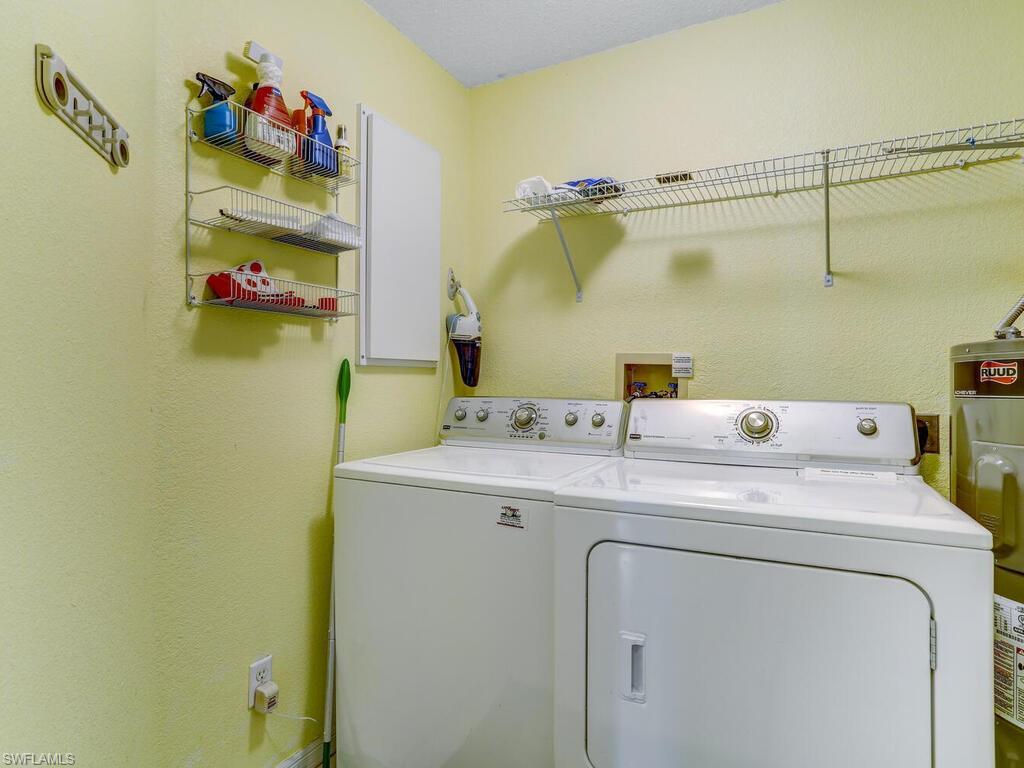 Laundry area featuring water heater, a textured wall, and separate washer and dryer