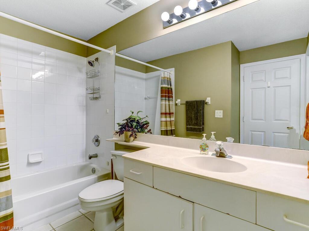 Full bath with light tile patterned flooring, vanity, and shower / bath combination with curtain