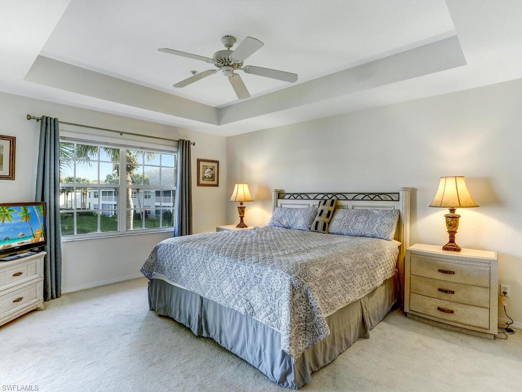 Bedroom with a raised ceiling, carpet, and ceiling fan