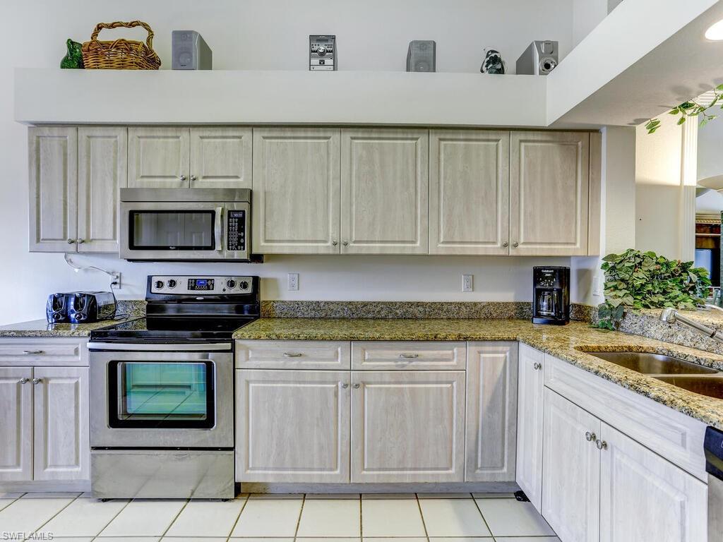 Kitchen with stainless steel appliances, light stone countertops, and light tile patterned floors
