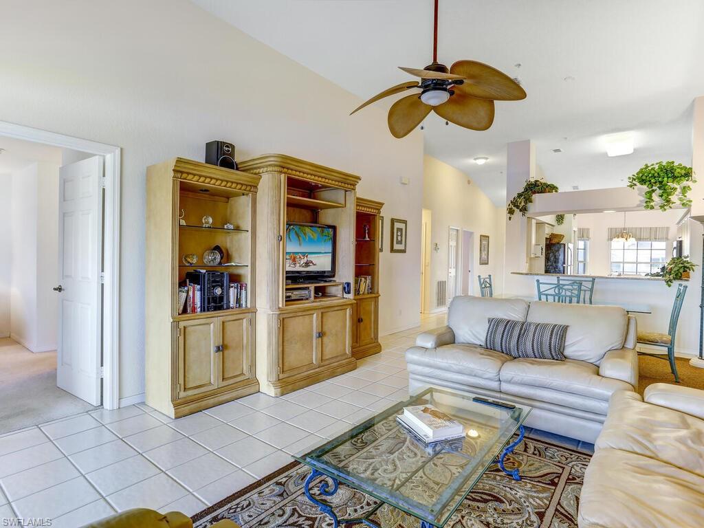 Living room featuring light tile patterned flooring, ceiling fan, and high vaulted ceiling