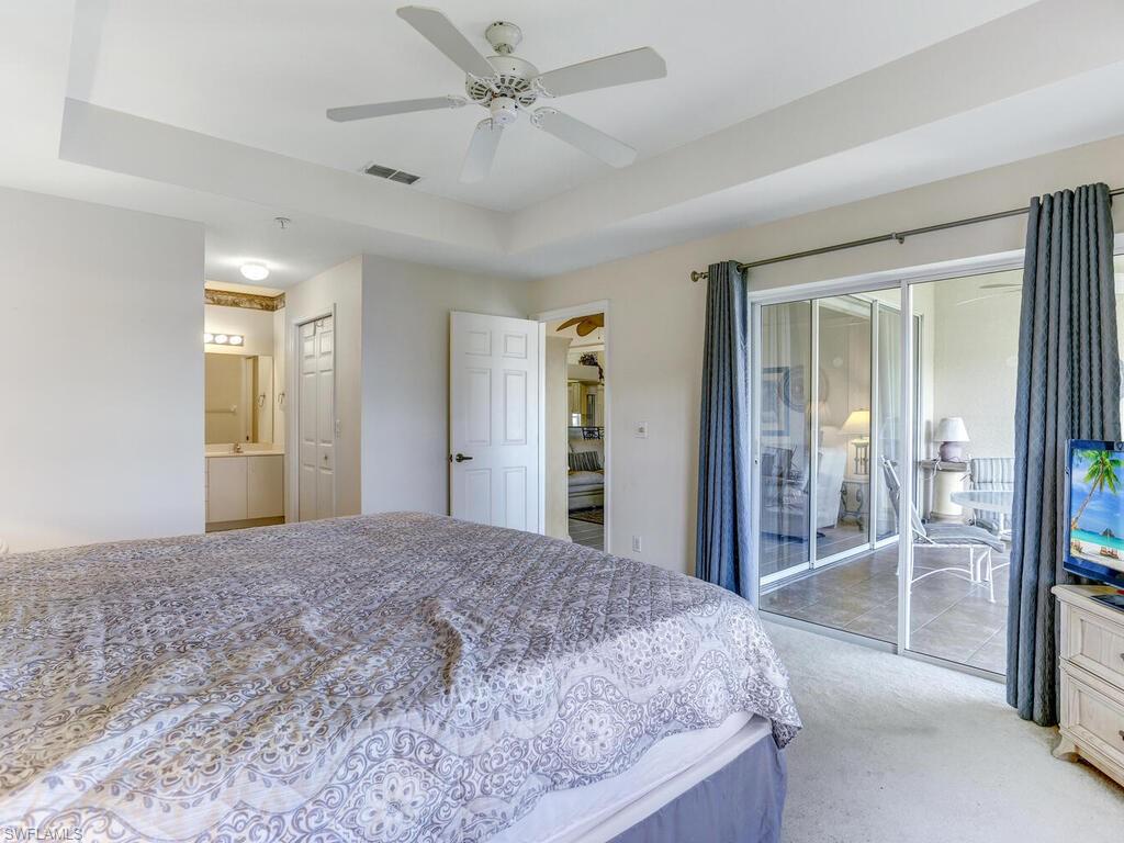 Carpeted bedroom with access to outside, a ceiling fan, and a raised ceiling