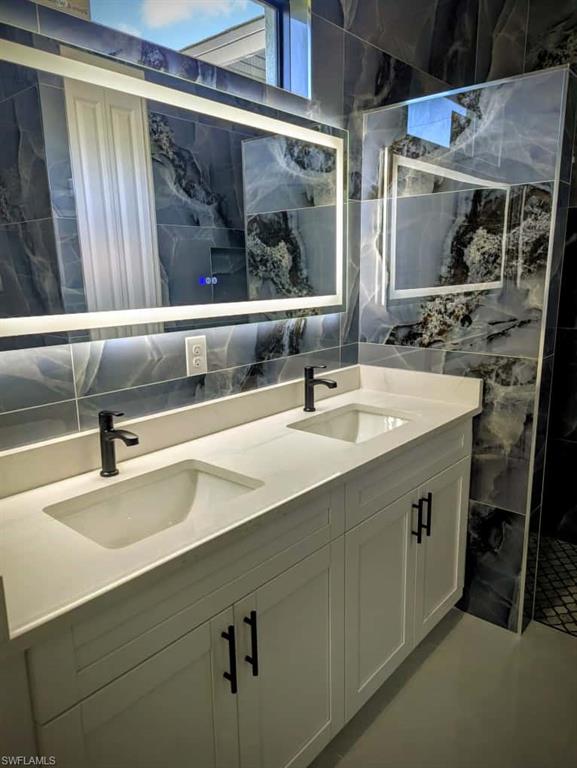 Bathroom with double vanity, tile walls, and decorative backsplash