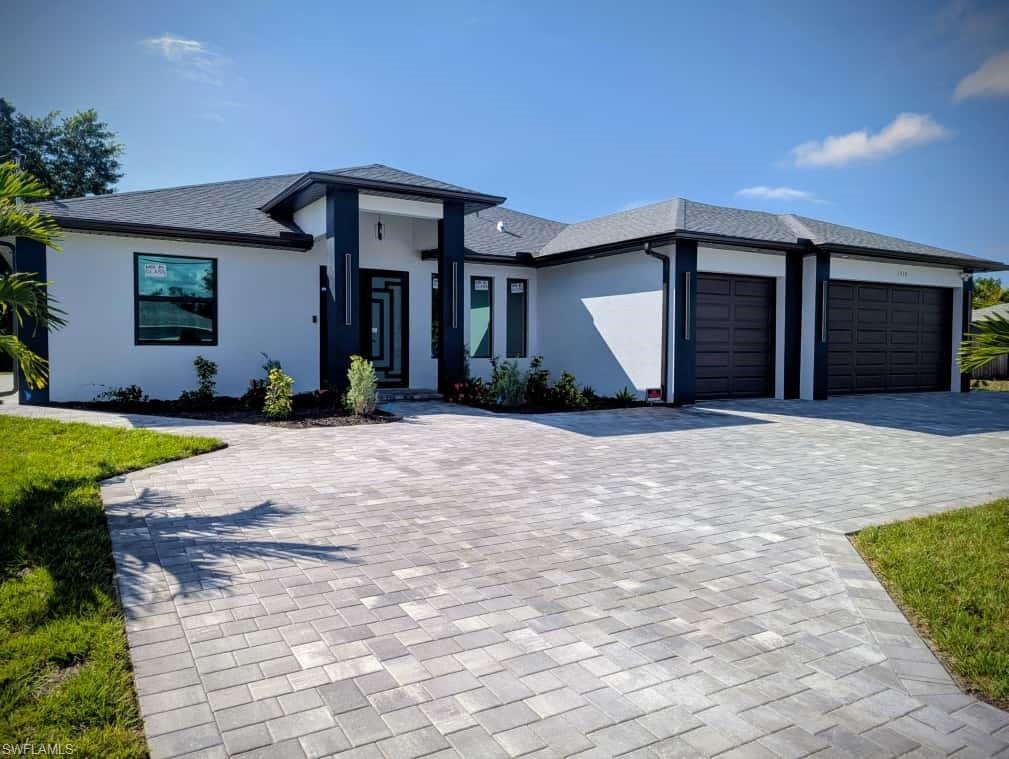 Prairie-style home featuring an attached garage, decorative driveway, stucco siding, and roof with shingles