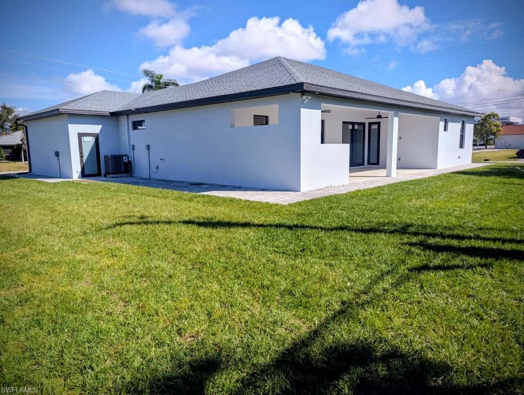 Back of house with stucco siding, a lawn, and a patio