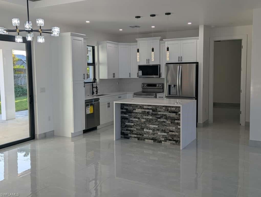 Kitchen featuring a center island, white cabinetry, appliances with stainless steel finishes, light stone counters, and recessed lighting