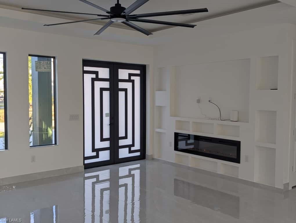 Foyer entrance with a glass covered fireplace, a ceiling fan, and light tile patterned floors