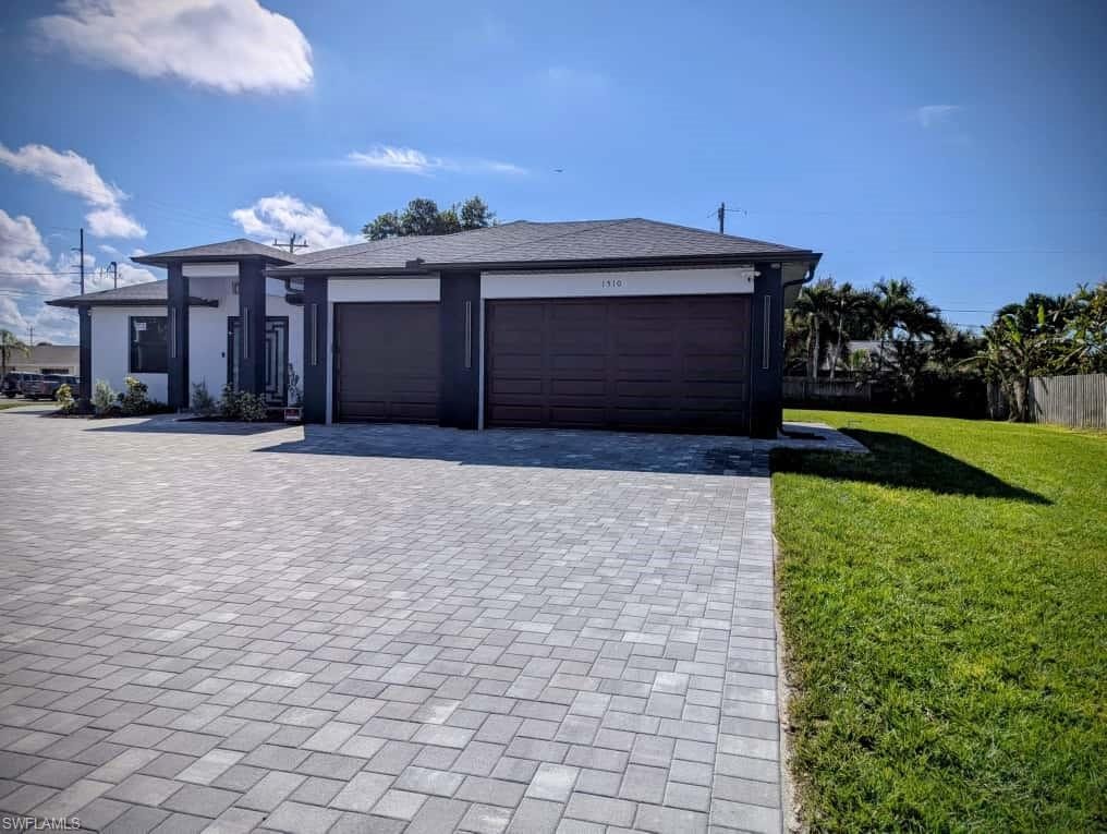 View of front of house featuring decorative driveway, a front lawn, stucco siding, and an attached garage