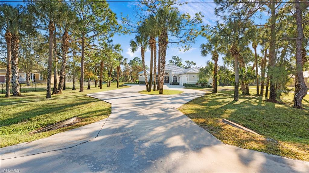 View of front of home with curved driveway and a front yard