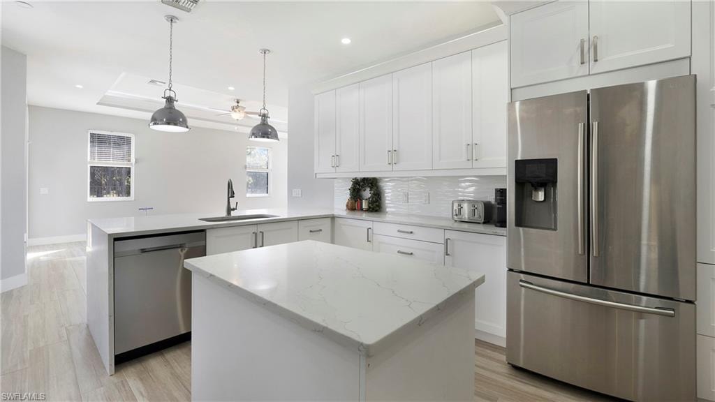 Kitchen with stainless steel appliances, light stone counters, white cabinets, a peninsula, and recessed lighting