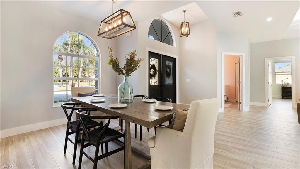 Dining space with french doors, light wood-style flooring, and a chandelier
