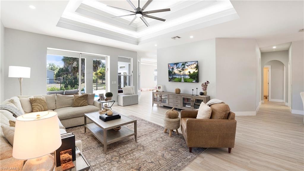 Living area with plenty of natural light, arched walkways, ornamental molding, light wood-style floors, and recessed lighting