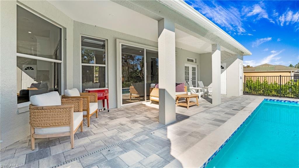 View of pool featuring a patio area, an outdoor living space, and french doors