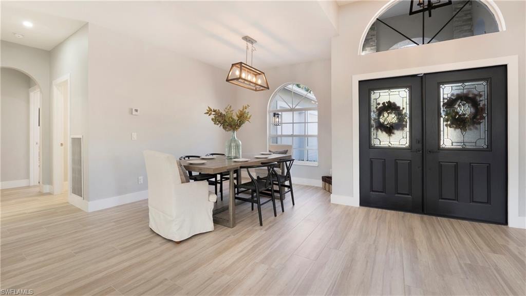 Entryway featuring french doors, arched walkways, and light wood-type flooring