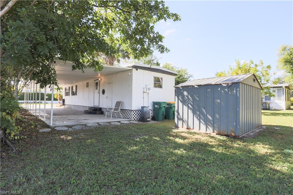 Rear view of property featuring a patio area, a yard, and a shed
