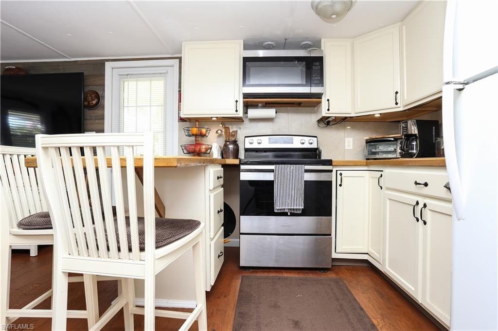 Kitchen featuring appliances with stainless steel finishes, dark wood finished floors, light countertops, and white cabinets
