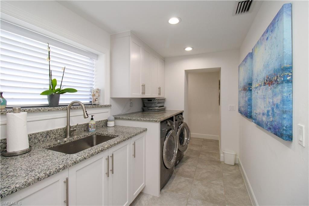 Laundry room with separate washer and dryer, sink, light tile patterned flooring, and cabinets