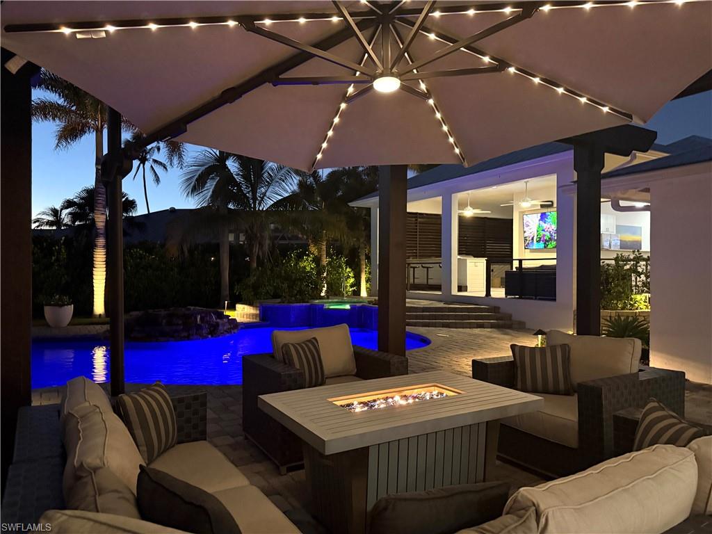 Patio terrace at dusk with ceiling fan and an outdoor living space with a fire pit