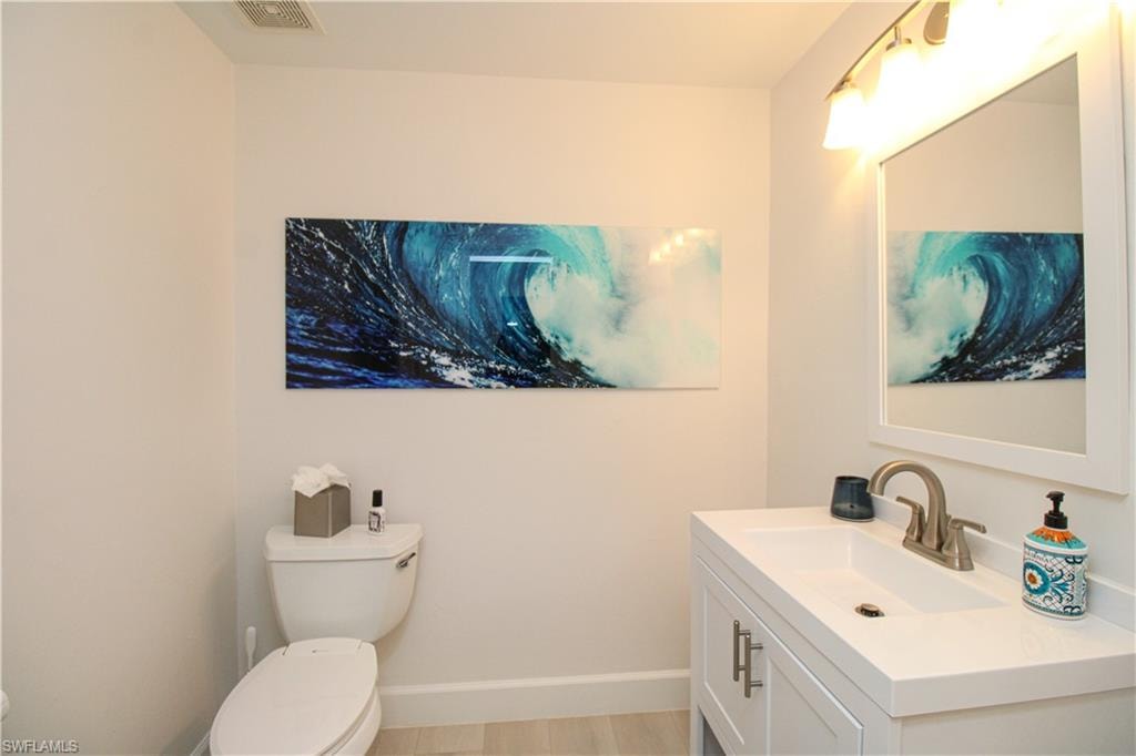 Bathroom featuring vanity, hardwood / wood-style flooring, and toilet