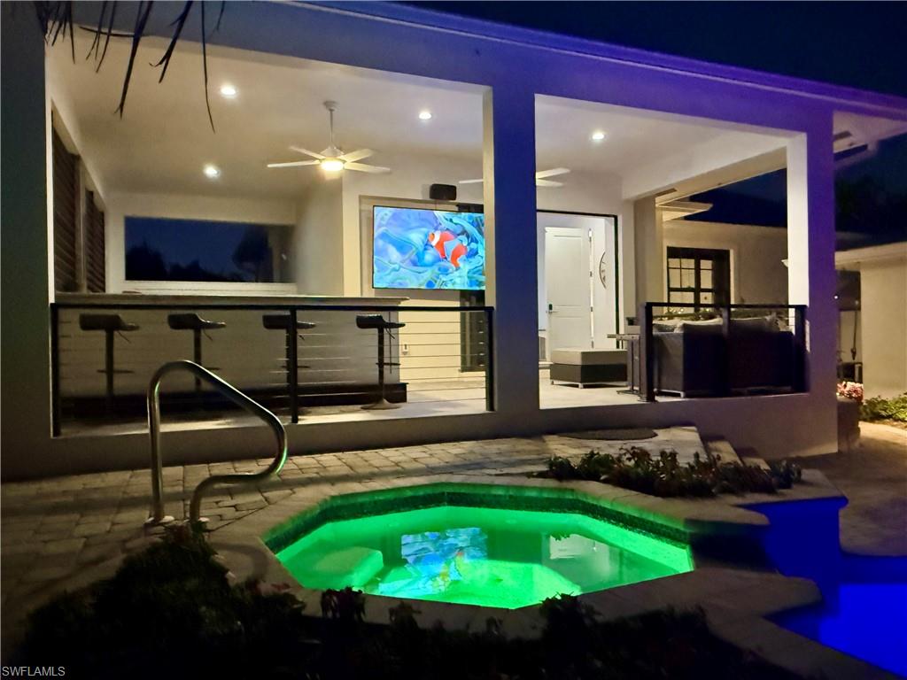 Pool at night with a patio area and ceiling fan