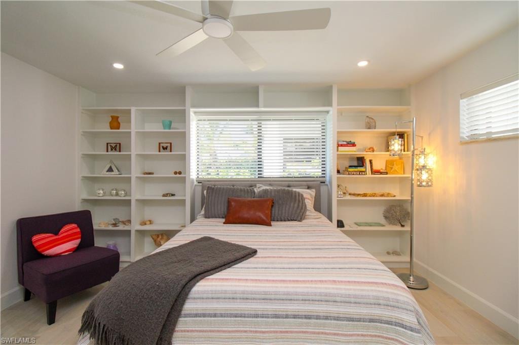 Bedroom with ceiling fan, light wood-type flooring, and multiple windows