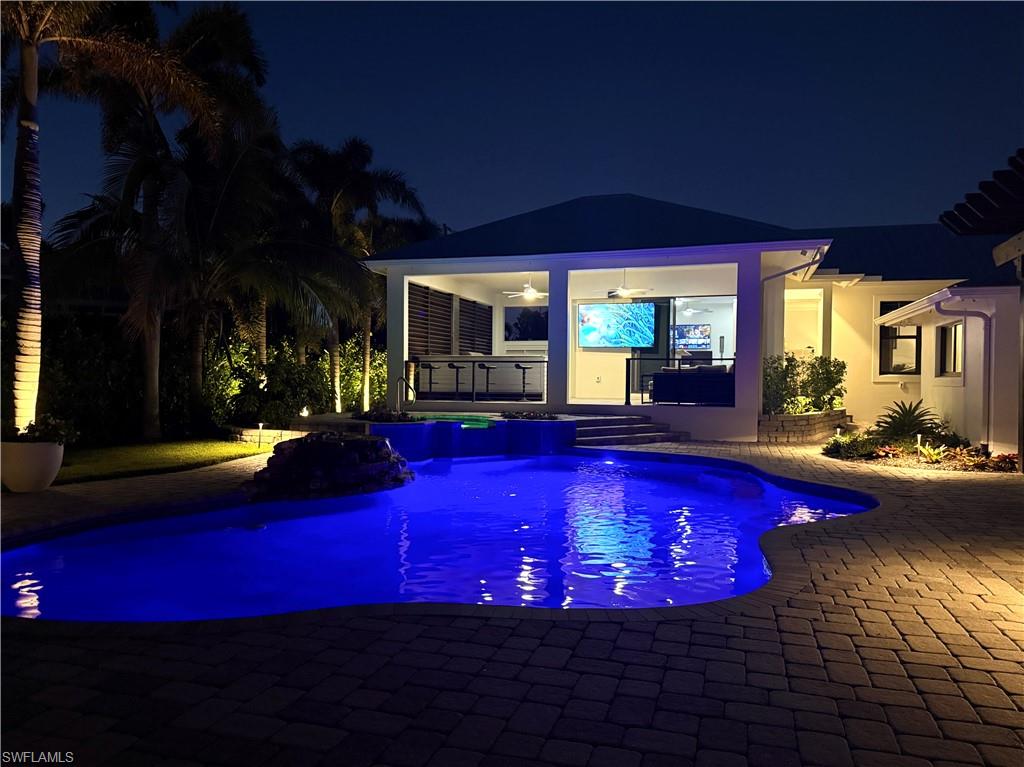Pool at night with a gazebo, ceiling fan, a patio area, and exterior bar