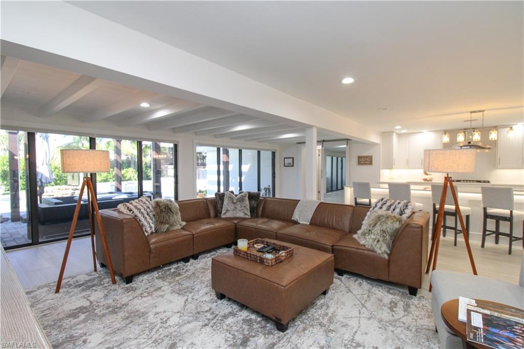 Living room featuring beamed ceiling, light hardwood / wood-style flooring, and a notable chandelier