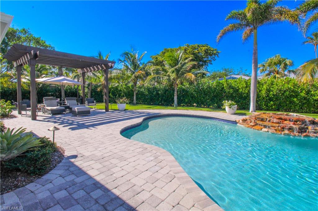 View of pool with pool water feature, a pergola, and a patio